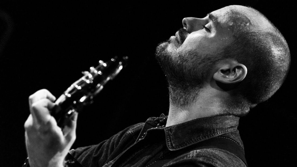 black and white photo of Andy McKee playing on stage with eyes closed