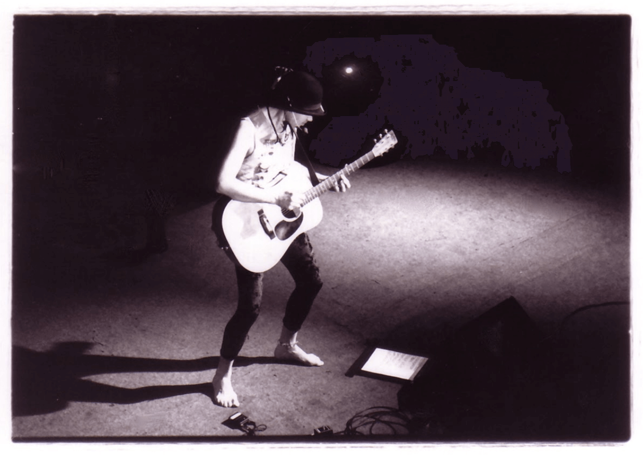 Michael barefoot on stage, playing guitar