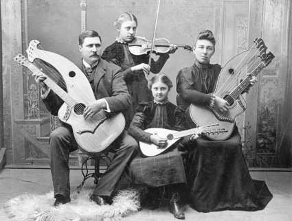 4 people sitting with various guitars