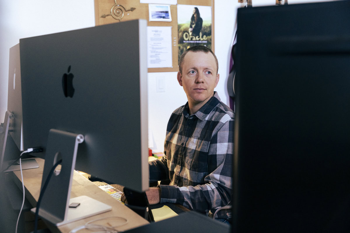 Filmmaker Mischa Hedges sitting at editing desk