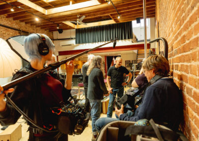 Jay Blakesberg and Mischa Hedges review guitar photos while documentary crew films. Photo Credit: Monica Semergiu